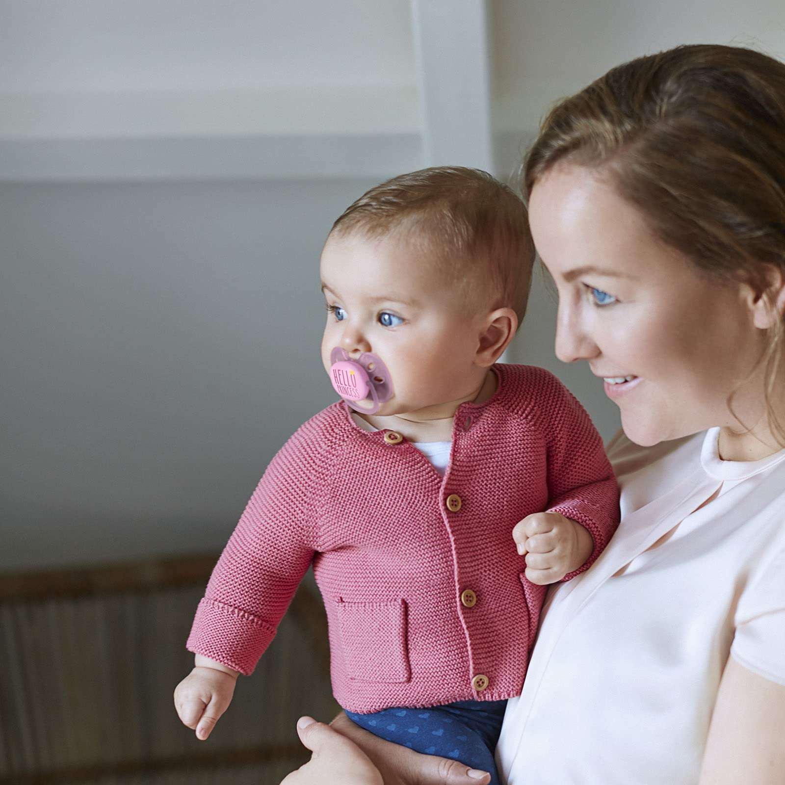 Mother holding baby with Philips Avent ultra soft pacifier UAE in pink showing soothing comfort and close parent bonding