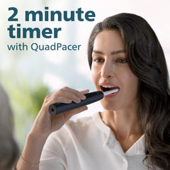 Woman using Philips Sonicare 4100 electric toothbrush UAE black model demonstrating 2 minute timer with QuadPacer