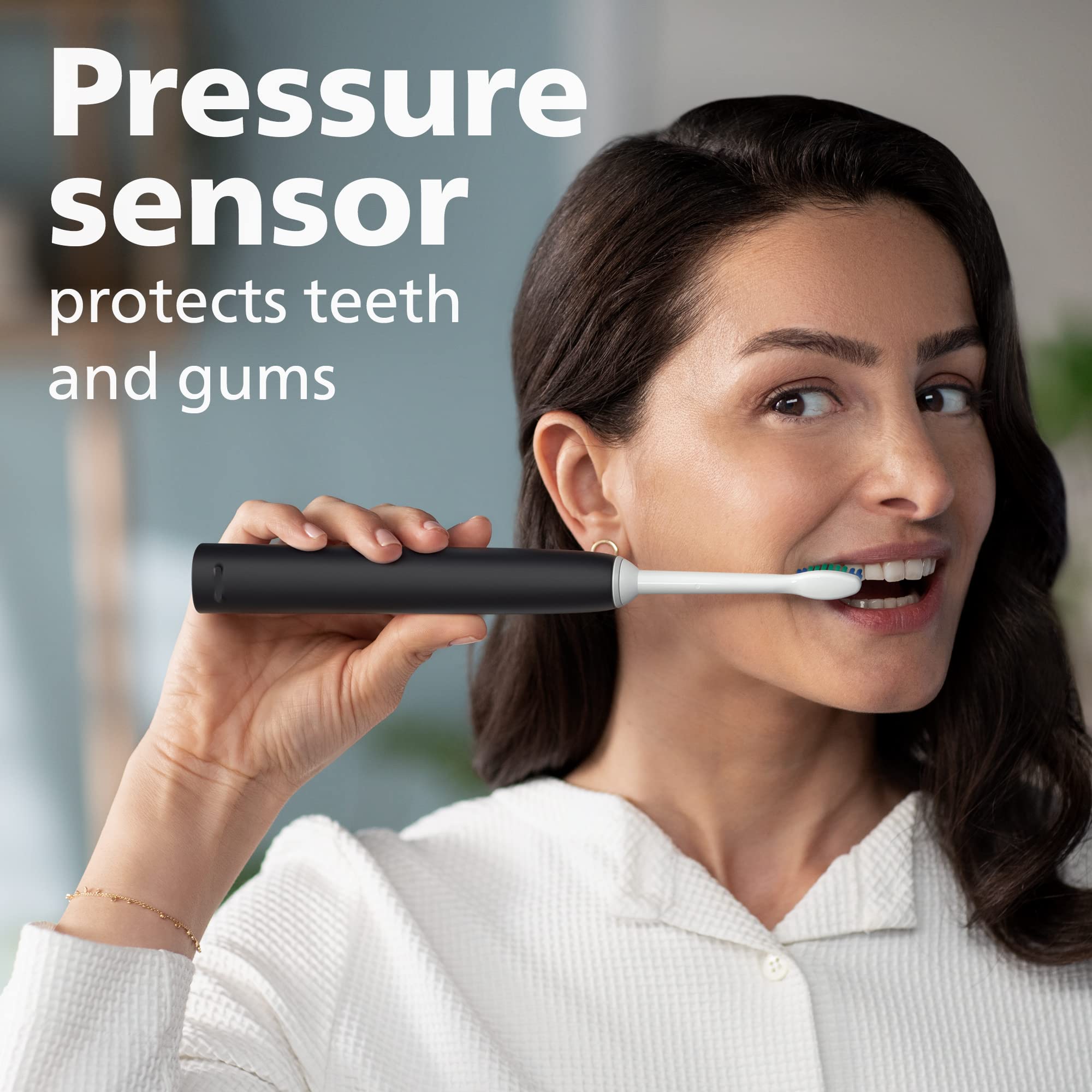Smiling woman brushing with black Philips Sonicare 4100 electric toothbrush UAE showing pressure sensor protecting teeth and gums