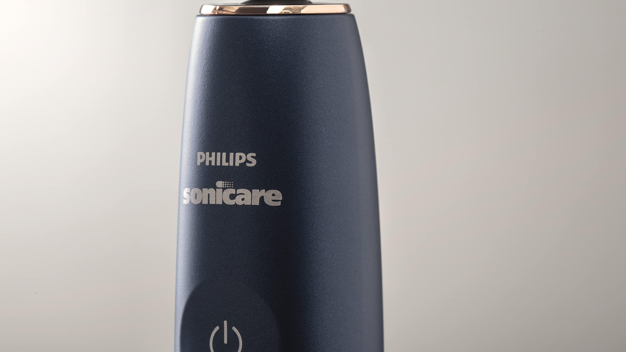 Close up navy Philips Sonicare 9900 Prestige toothbrush handle showing PHILIPS logo and power button