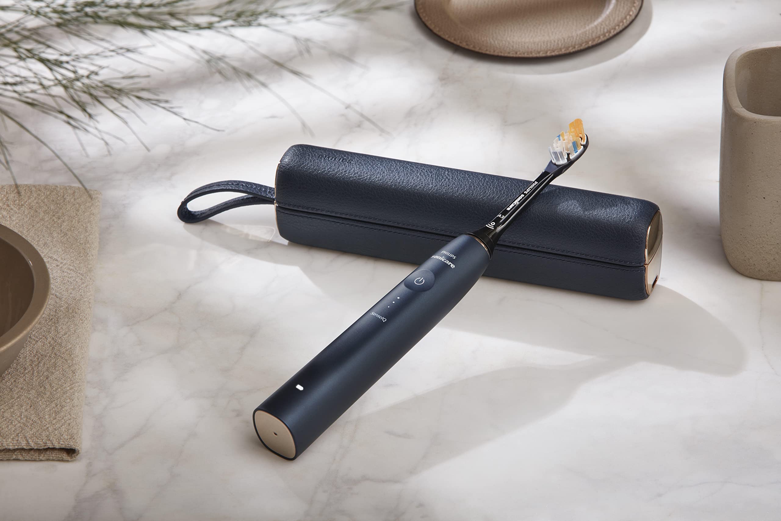 Philips Sonicare 9900 Prestige toothbrush in matte navy with leather travel case on marble countertop