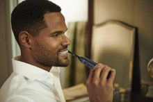 Man brushing teeth with midnight blue electric toothbrush