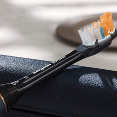 Black electric replacement head with white blue and orange bristles on textured surface Philips Sonicare Premium brush heads