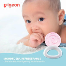 Pink circular cooling teether with white ring handle held by a baby close-up