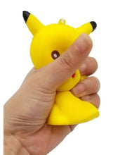 Pikachu yellow stress relief squeeze toy being squeezed in hand, ear tips visible