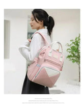 Pink baby travel backpack with gray zipper, front pocket, and top carry handles