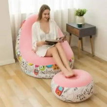 Pink inflatable lounge chair with graphic pattern and round footrest, shown in use