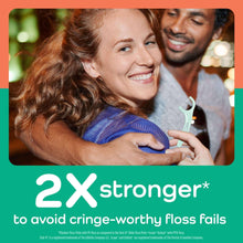 Mint-colored dental floss pick being used between teeth.