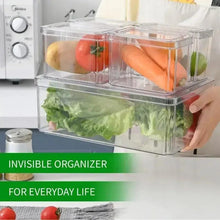 Clear refrigerator food organizer box with compartments, leafy greens inside, hand adjusting lid
