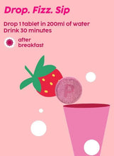 Effervescent strawberry tablet drop in water glass with fizz and foam bubbles