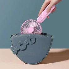 Pink portable handheld fan with button handle, held in hand