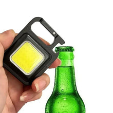 Black mini LED pocket light with carabiner clip and USB cable, glowing yellow panel