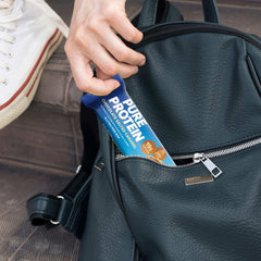 Pure Protein protein bar chocolate salted caramel in blue wrapper placed into black backpack for on the go snack