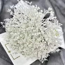 White artificial flower bouquet with dense small blossoms and visible stems