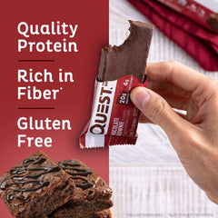 Quest chocolate brownie protein bars held in hand with a bite taken showing chocolate drizzle and gluten free label