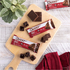 Quest chocolate brownie protein bars on a wooden cutting board with unwrapped bars and brownie pieces