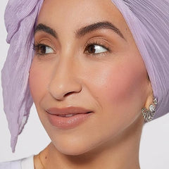 Close-up of a woman wearing Rare Beauty Soft Pinch Liquid Blush with natural makeup and a lavender headscarf