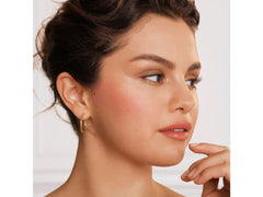Young woman with glowing skin wearing Rare Beauty Soft Pinch Liquid Blush in a natural pink shade