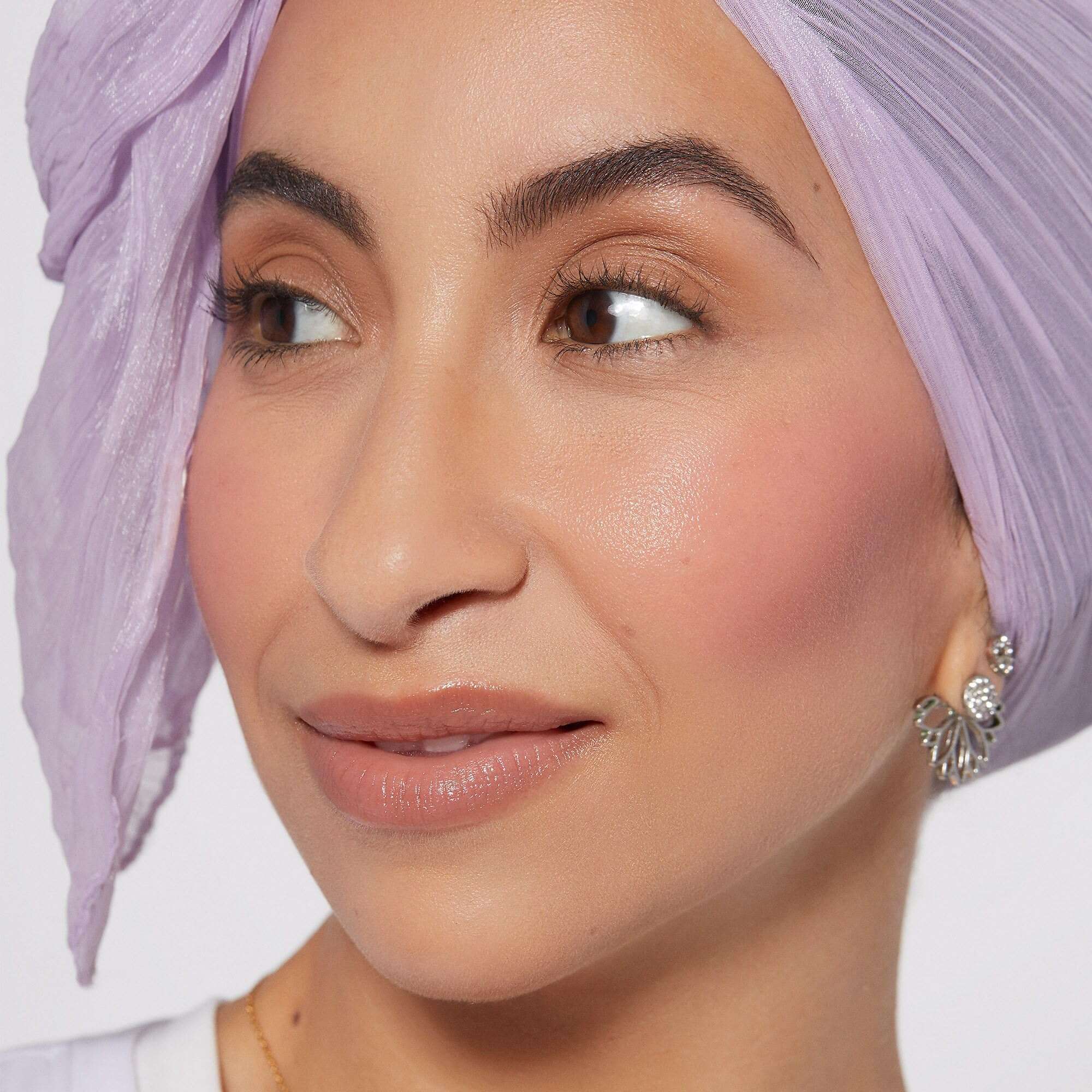 Close-up of woman wearing Rare Beauty Soft Pinch Liquid Blush with natural makeup and lilac headscarf