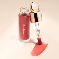 Rare Beauty Soft Pinch Liquid Blush bottle with applicator brush and smooth coral pink blush swatch