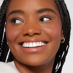 Close-up of smiling woman wearing Rare Beauty Soft Pinch Liquid Blush with glowing skin