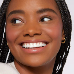 Close-up of smiling woman wearing Rare Beauty Soft Pinch Liquid Blush by YAMOOCO on cheeks