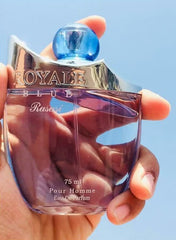 Rasasi Royale Blue perfume for men in a stylish bottle held against a clear blue sky