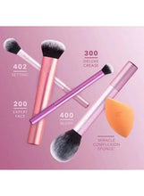 Five Real Techniques makeup brushes with pink and purple handles and an orange sponge