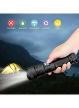 Black flashlight held in hand, shining a bright beam toward a tent outdoors