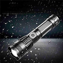 Silver-and-black flashlight with textured grip, water droplets and bright front beam