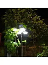 Hanging LED lantern casting bright light under outdoor tree leaves