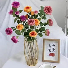 Artificial rose bouquet in clear glass vase with green leaves