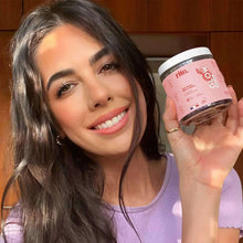Vegan vitamin gummies bottle held in hand; pink label and dark gummies visible