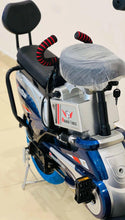 Electric scooter front side with covered seat, red coil springs, blue/white body, kickstand