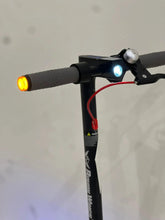 Electric scooter handlebar close-up with left amber turn light and headlight