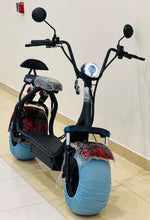Electric scooter standing indoors with headlight and blue wheel covers