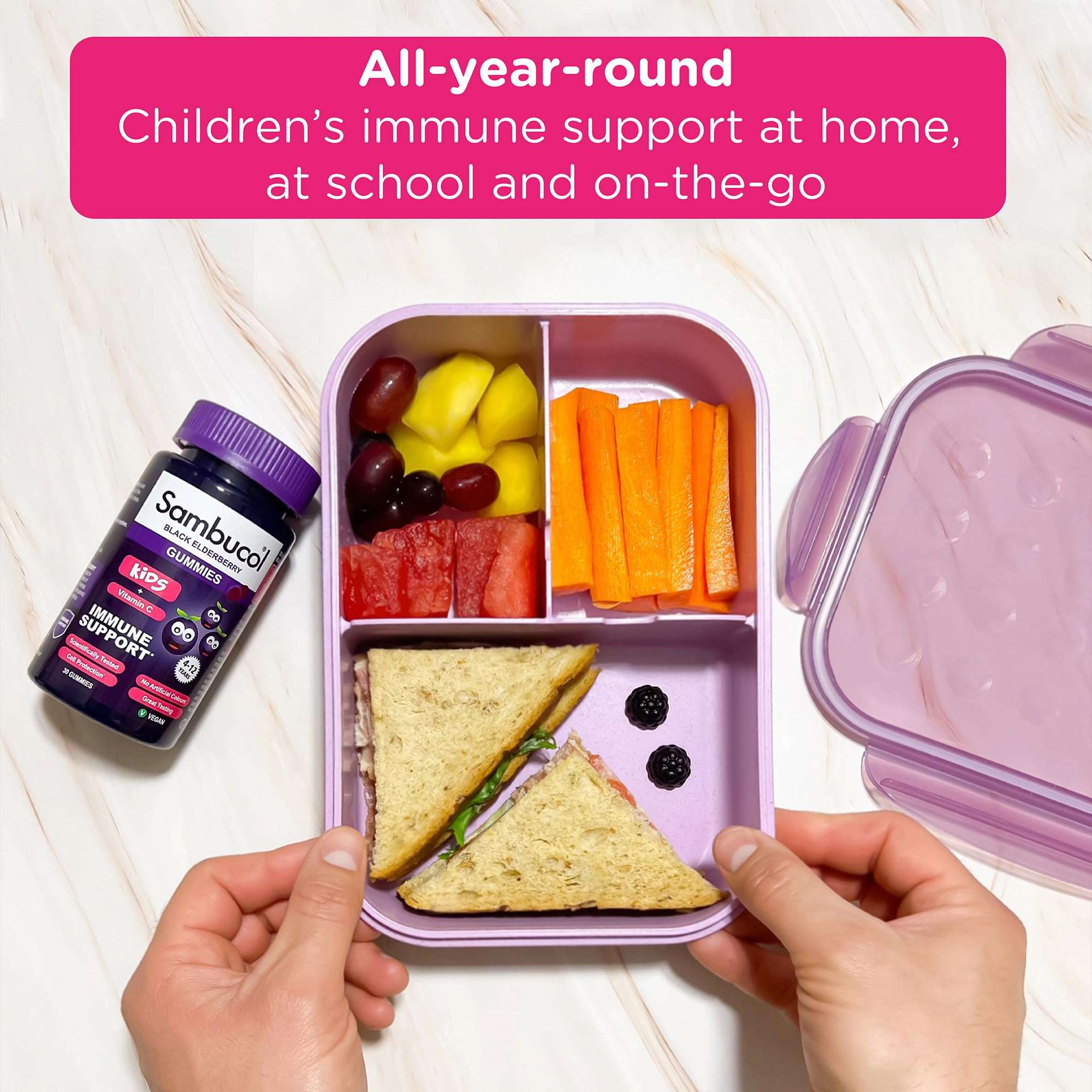 Sambucol bottle beside a purple lunchbox with sandwich fruit and carrots showcasing kids immune support gummies for school lunch