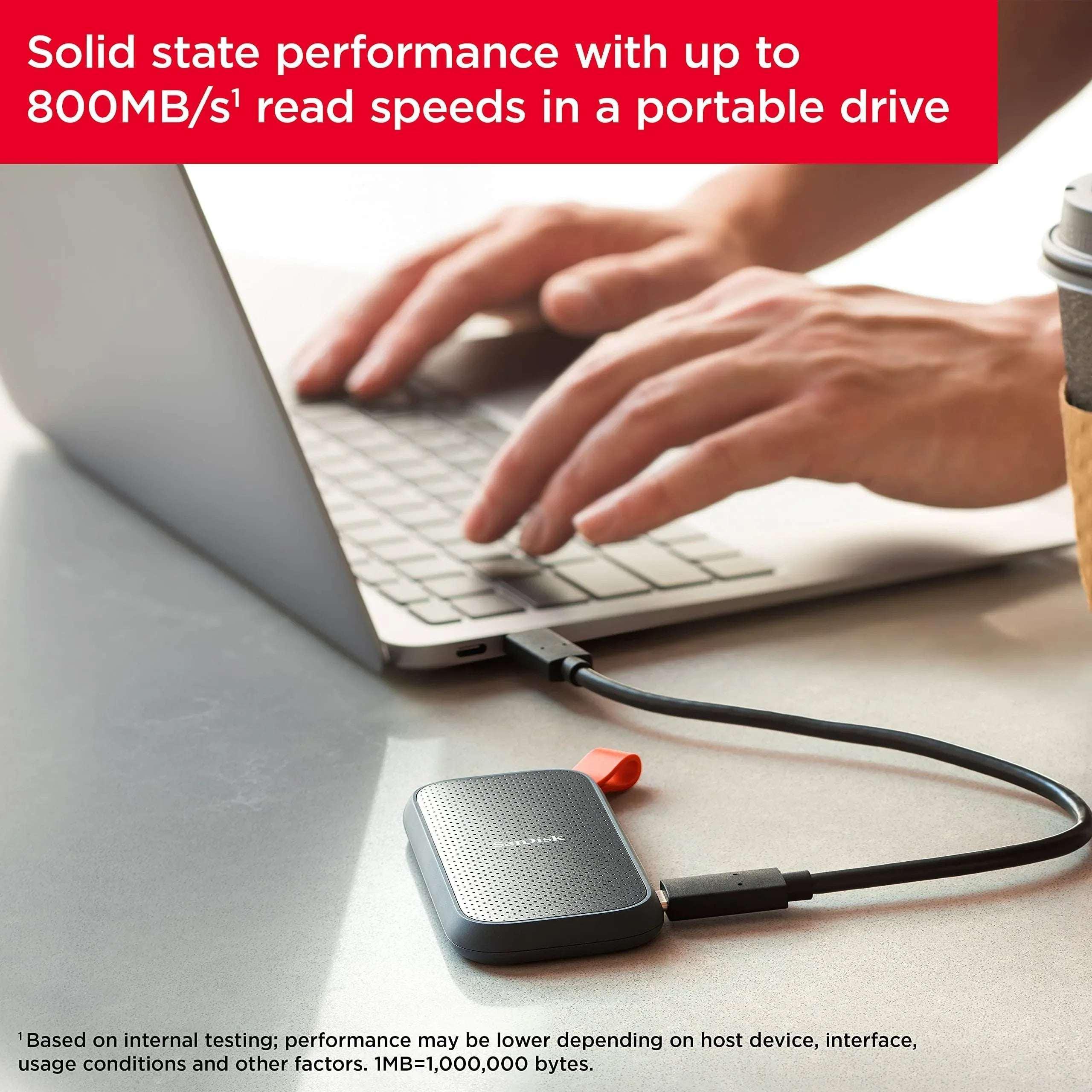 SanDisk external SSD connected by black cable, orange-tipped USB-C end