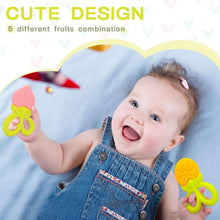 Baby wearing denim overalls holding a green silicone fruit teether