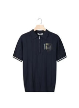 Short-sleeve polo shirt in dark navy with white trim on sleeves, chest logo, half-zip.
