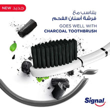 Charcoal toothbrush with black bristles shown with Signal charcoal toothpaste tube
