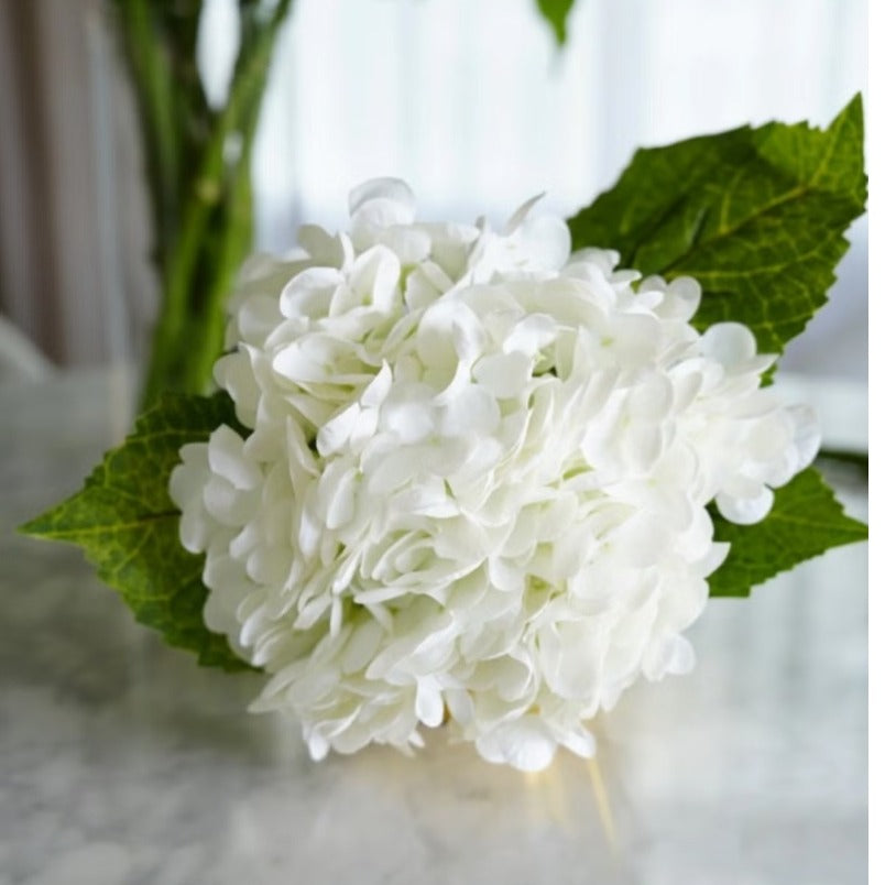 Huitich artificial white silk hydrangea blooms for home decor with green leaves on marble surface