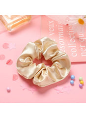 Huitich silk scrunchie for women in champagne color placed on pink surface with decorative items