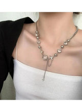 Silver-tone charm necklace with oval beads, star charm, and long cross drop