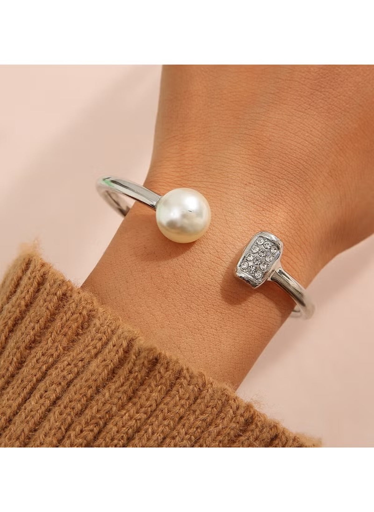 Huitich silver cuff bracelet with pearl and crystal accents on wrist with brown sweater