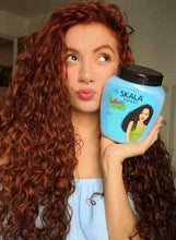 Woman holding Mais Cachos hair cream bottle; light blue with dark cap