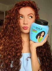 SKALA curl defining hair cream in blue jar held by a woman with curly red hair, promoting defined curls