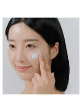 Woman applying a light blue sunscreen cream to her cheek