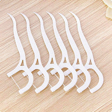 White plastic dental floss picks laid in a row, close-up on wood surface
