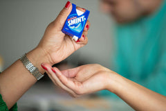 Blue Smint sugarfree mints pack being handed from one person to another over open palm